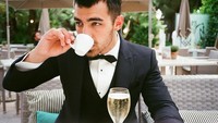 Minum kopi ditemani segelas champagne, memang bukan perpaduan yang pas. Tapi dengan pose keren Joe, semuanya terlihat cocok. Foto: Instagram @joejonas