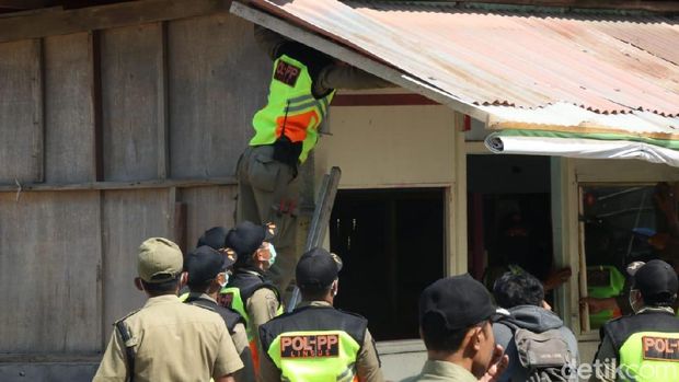 Petugas Satpol PP membongkar rumah-rumah semipermanen. 