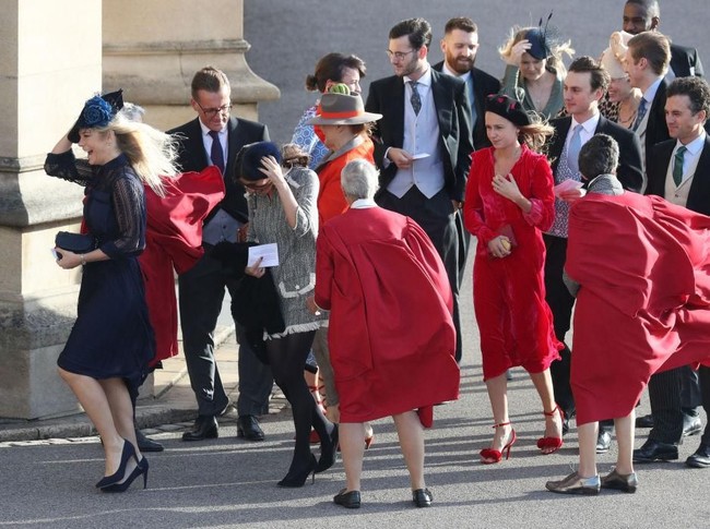 Chelsy memilih gaun biru navy dengan aksen panel transparan pada bagian lengan. Tampak di foto, Chelsy dan tamu lainnya kewalahan melawan tiupan angin yang begitu kencang di area Windsor Castle. (Foto: Getty Images)