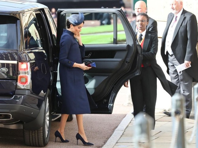 Meghan Markle muncul dalam balutan gaun biru navy bersiluet coat dari Givenchy rancangan Clare Waight. (Foto: Getty Images)