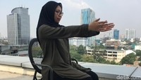 Coba peregangan pertama dengan duduk di atas kursi yang tegap, kaki datar di lantai. Gantung tangan di samping tubuh dengan rileks, kedua telapak tangan menghadap satu sama lain. Perlahan angkat tangan menuju ke depan di atas lutut. (Foto: Frieda Isyana Putri/detikHealth, Model: Annissa Widya Davita)