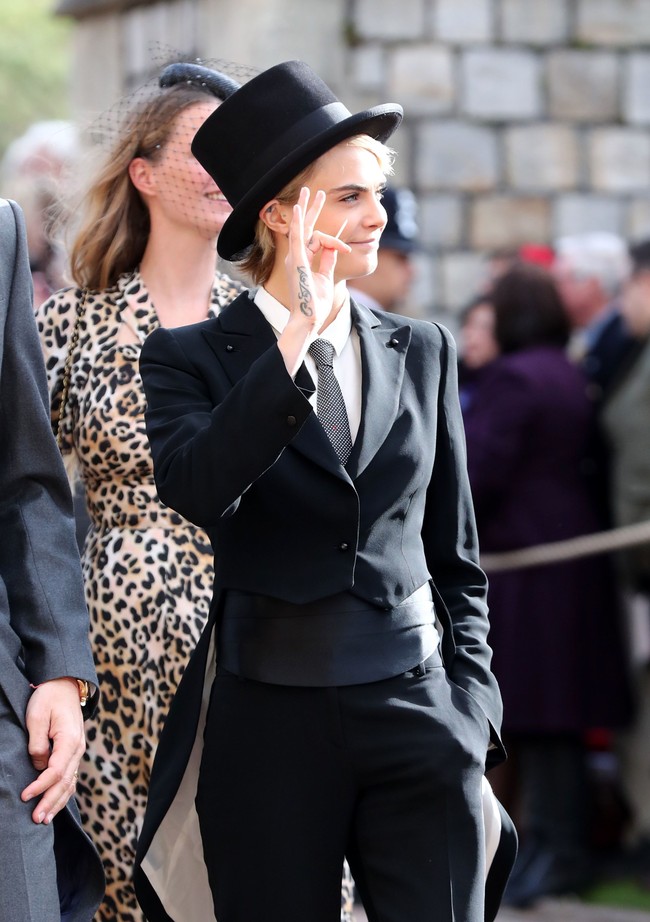 Cara Delevingne bukan tampil dengan coat dress atau gaun cantik, melainkan setelan tuksedo pria klasik khas Inggris untuk pernikahan Putri Eugenie. Tak hanya tuksedo, model favorit Chanel itu melengkapi setelannya dengan topi. Foto: Dok. Getty Images