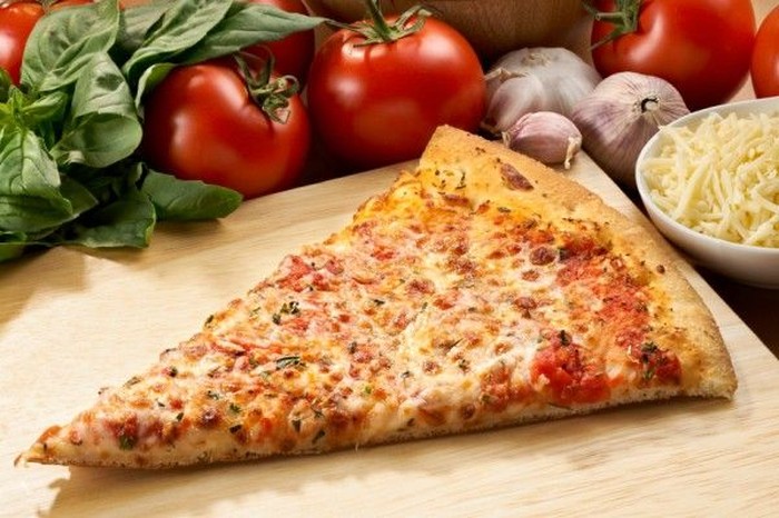 Supreme meat and vegetable pizza on stone in wood-fired oven with open flames