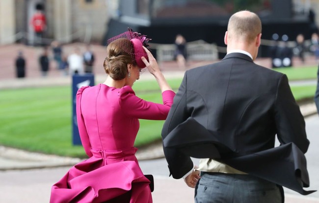 Kate saat tiba di Kastil Windsor bersama Pangeran William jelang pernikahan Putri Eugenie. Ia tampak berusaha menjaga topinya agar tak terbang ditiup angin. Foto: Getty Images