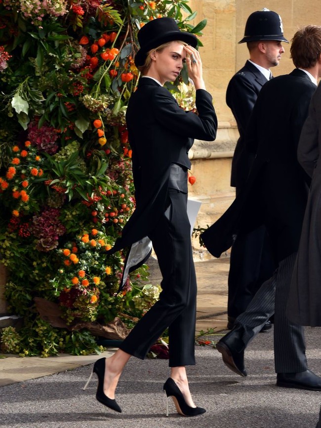 Cara Delevingne hadir di pernikahan Putri Eugenie di Windsor Castle, Inggris, Jumat (12/10/2018), mengenakan setelan tuksedo hitam dilengkapi topi dan high heels berwarna senada. Foto: Getty Images