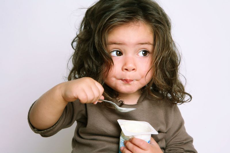 little boy eating yogurt on a white background