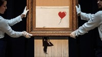 Secara dramatis, lukisan Girl with Balloon yang menampilkan anak perempuan tengah memegang balon bergambar hati itu usai ketok palu, kanvas diturunkan dan dirobek oleh mesin penghancur kertas sampai setengah bagian.  Foto: Getty Images