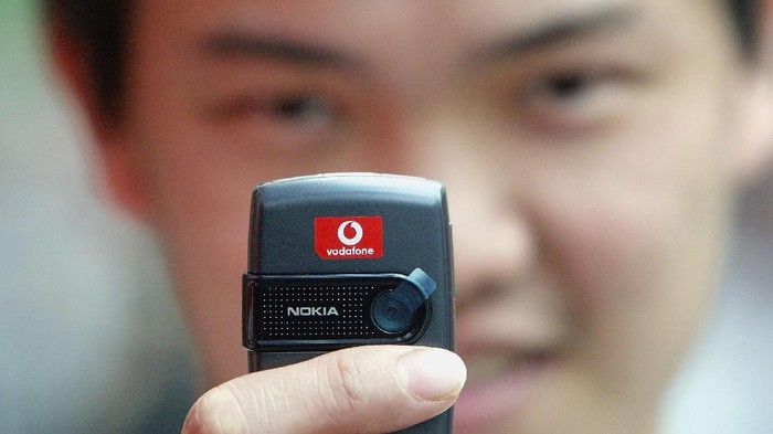 LONDON - MAY 25:  A man takes a phototograph using his Vodafone mobile phone on May 25, 2004 in London, England. Mobile phone giant Vodafone has cut its full-year losses to ?5bn ($8.9bn) due  to an increase in customer numbers,  an improvement on last years ?6.2bn loss. (Photo by Scott Barbour/Getty Images)