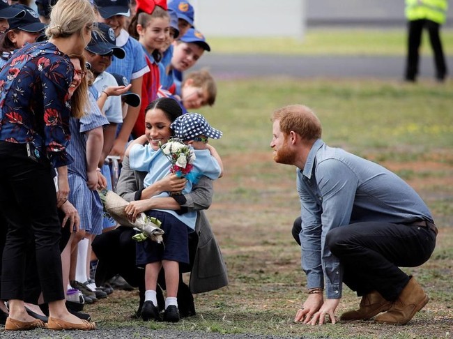 Disaksikan Pangeran Harry, Meghan Markle memeluk murid sekolah saat berinteraksi dengan warga lokal. Sudah cocok yah jadi ibu? Seperti marak diberitakan sebelumnya, Meghan saat ini tengah hamil anak pertamanya bersama Pangeran Harry. Kandungannya sudah memasuki usia 12 minggu. (Foto: Getty Images)