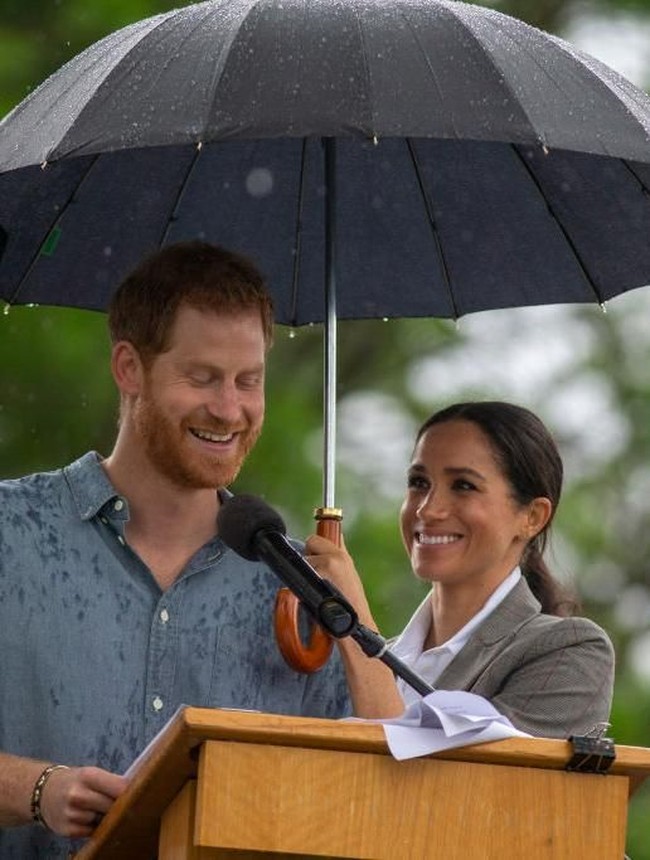 Hujan deras juga tak menghalangi Pangeran Harry untuk tetap berpidato di luar ruangan. Bukan pengawal pribadi, melainkankan Meghan yang memayungi sang suami saat berpidato. So sweet! (Foto: Getty Images)