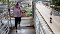 Seorang warga terlihat sangat berhati-hati saat melintas di JPO.