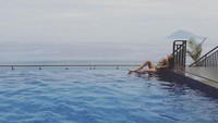 Ia pun tak menyia-nyiakan momen untuk berpose dengan latar laut dan infinity pool. Tampak juga sebuah gunung di kejauhan (17.putrijuby/Instagram)