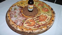 Lalu ada sebotol bir yang berdiri tegap di atas pizza. Nah, kalau restoran pizza ini ada di Indonesia, kamu tertarik untuk datang dan membelinya nggak? Foto: Facebook pizzariabatepapo