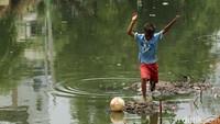 Sesekali mereka harus turun ke kali untuk mengambil bola yang tercebur.
