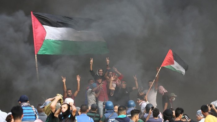 A woman holds a Palestinian flag during a protest calling for lifting the Israeli blockade on Gaza and demanding the right to return to their homeland, at the Israel-Gaza border fence in Gaza October 19, 2018. REUTERS/Mohammed Salem