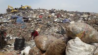 Sejumlah orang sedang memisahkan jenis sampah. Di belakangnya, ada dua eskavator yang membolak-balik sampah. (Isal Mawardi/detikcom)