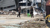 Dua polisi nampak berjaga-jaga di depan gudang yang rusak diterjang tsunami. (Latif Harnoko/detikcom)