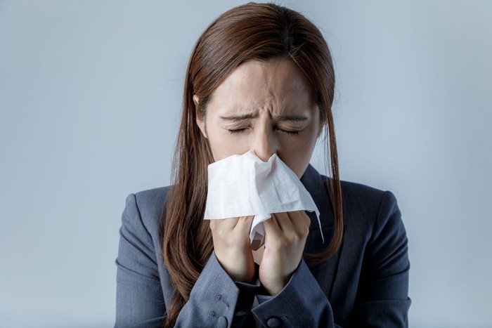 Ilustrasi ingus Sick Woman Sneezing in to Tissue Paper