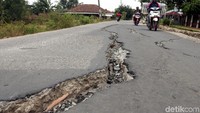 Pengendara sepeda motor melintas di jalan yang retak, Senin (22/10/2018).