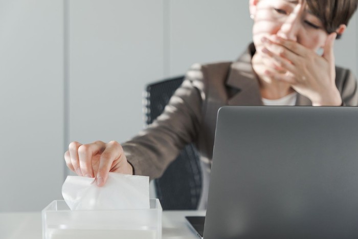 Sick Woman Sneezing in to Tissue Paper