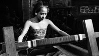 Seorang putri kepala desa di Bali sedang menenun kain pada tahun 1954. Three Lions / Getty Images.