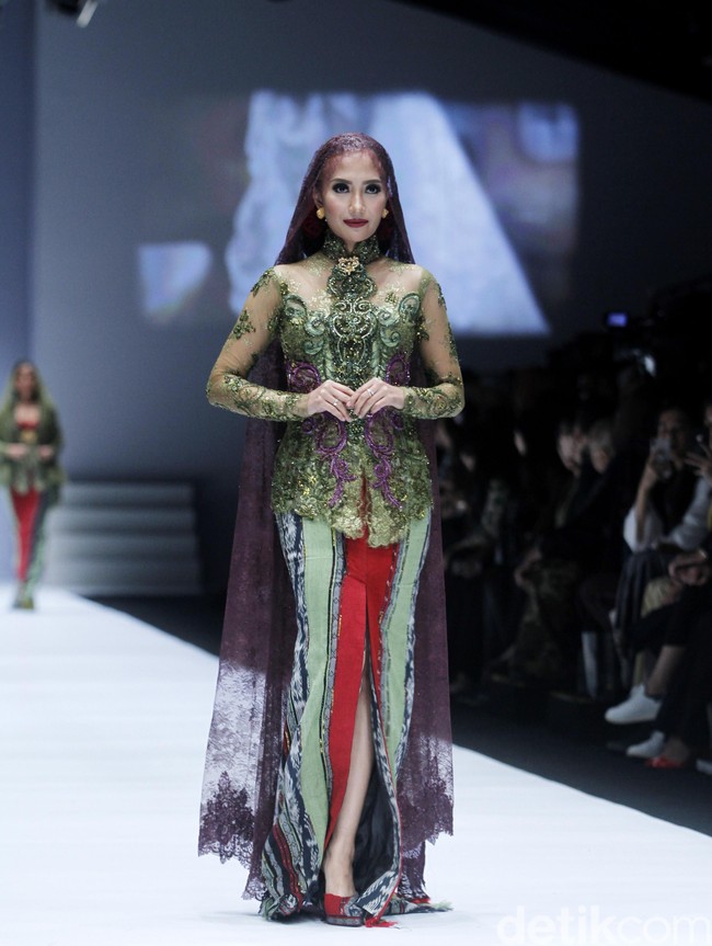 Penampilan dramatis diberikan oleh Puteri Indonesia 2004 Artika Sari Devi. Berjalan dengan wajah fierce, Artika terlihat memakai kebaya hijau dengan veil panjang berwarna ungu saat menjadi model Anne Avantie di Jakarta Fashion Week 2019. Foto: Mohammad Abduh/Wolipop
