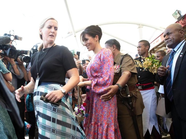 Inilah sosok bodyguard perempuan (kiri berbaju hitam) yang namanya dirahasiakan tersebut saat ditugaskan dalam tur perdana Pangeran Harry dan Meghan Markle ke Australia dan sekitarnya. Foto ini diambil ketika Meghan berkunjung ke sebuah pasar tradisional di Suva, Fiji, Rabu (24/10/2018). (Foto: Getty Images)