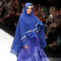 Mulan berlenggak-lenggok di catwalk Jakarta Fashion Week 2019 dalam balutan dress berdetail ruffle berwarna biru. Dia memakai khimar yang sewarna dengan bajunya. Wanita yang kini menjadi istri Ahmad Dhani itu melengkapi gayanya dengan memakai kalung mutiara sebagai hiasan kepala. Foto: Ismail/detikFoto