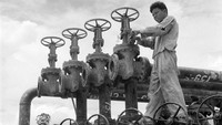 Seorang pekerja mengoperasikan katup pengontrol saluran pipa di kilang minyak di Sumatra pada 1955. Three Lions/Getty Images.