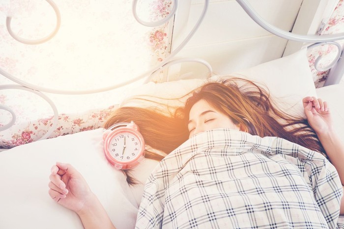 618730242 Close up Woman sleeping on bed in Morning with Alarm clock