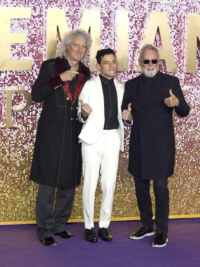 Rami Malek berpose bersama dua personel Queen, gitaris Brian May dan drummer Roger Taylor, saat menghadiri premier film Bohemian Rhapsody di London, Inggris, Rabu (25/10/2018). Rami menebar pesonanya dalam balutan setelan bernuansa monokrom. (Foto: Getty Images)