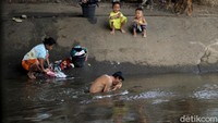 Mulai dari mencuci baju, mandi, hingga bermain dibantaran kali bagi mereka sudah biasa dilakoni sehari-hari.