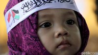 Seorang Balita mengenakan atribut sebuah ikat kepala dengan lambang bendera Indonesia dan bendera Palestina.