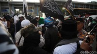 Massa membawa bendera bertuliskan kalimat tauhid.
