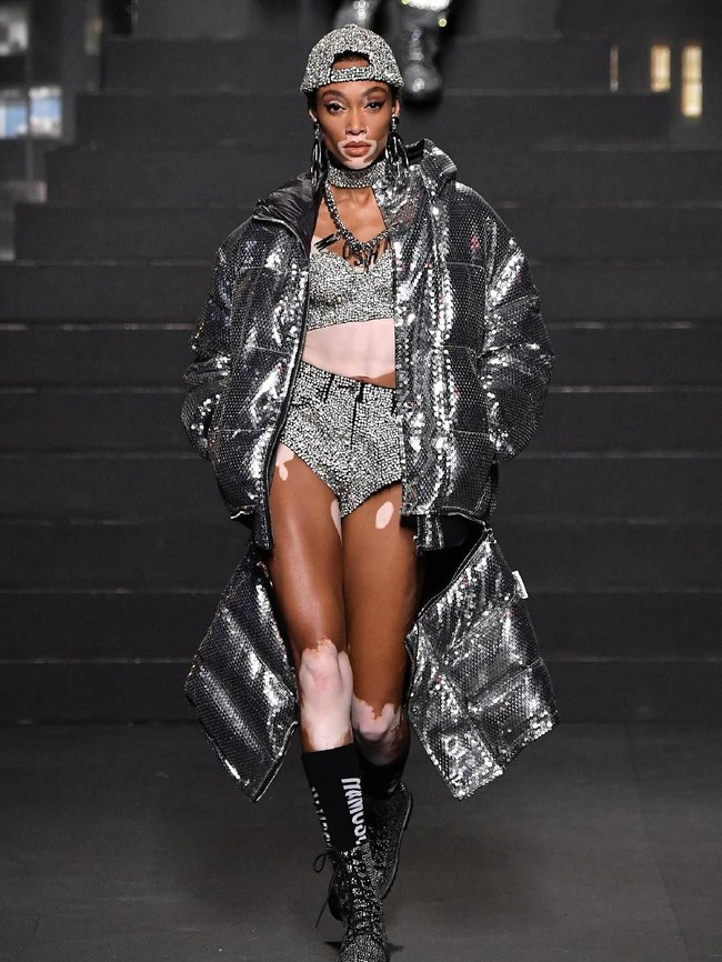 Model Winnie Harlow pun tak kalah menarik perhatian. Gaya swag diadaptasi dalam tampilan kekinian dengan coat tebal warna silver, topi berhias kristal serta setelan crop top dan short pants. (Foto: Getty Images)