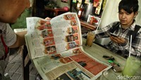 Seorang warga membaca edisi terakhir tabloid Bola.
