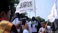 Tampak seorang ayah mengambil foto anaknya yang mengibarkan bendera dalam aksi bela tauhid tersebut.
