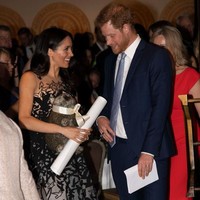 Meghan menyempurnakan gayanya dengan sepasang sling-back heels hitam yang menopang kedua kakinya. Foto: Paul Edwards - Pool/Getty Images