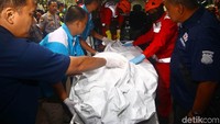 Petugas tampak hati-hati saat menurunkan kantong jenazah tersebut.
