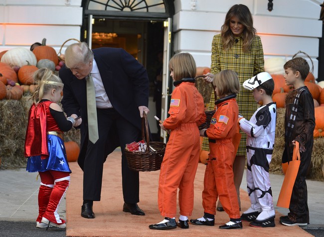 Melania mengikuti acara trick-or-treat di Gedung Putih dibalut coat dress kuning bermotif plaid dari Bottega Veneta. Padanan bersama sepatu pump hitam sederhana melengkapi kostum Halloween Melania Trump. Foto: Dok. Getty Images