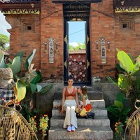 Udara Bali yang panas tampaknya membuat Kourtney merasa nyaman tampil dengan bralette atau crop top. Ketika berpose di depan bangunan khas Bali bersama sang putri, ia menggunakan bralette cokelat yang dipadukan dengan celana putih longgar serta sneakers. Foto: Instagram @kourtneykardash