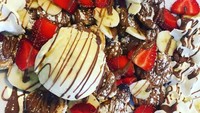 Ada es krim, saus cokelat, irisan buah strawberry dan pisang, serta whipped cream yang memenuhi sepiring poffertjes buatan @thechocolateroomuk.