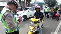 Polisi menilang pengendara motor yang melanggar lalu lintas.