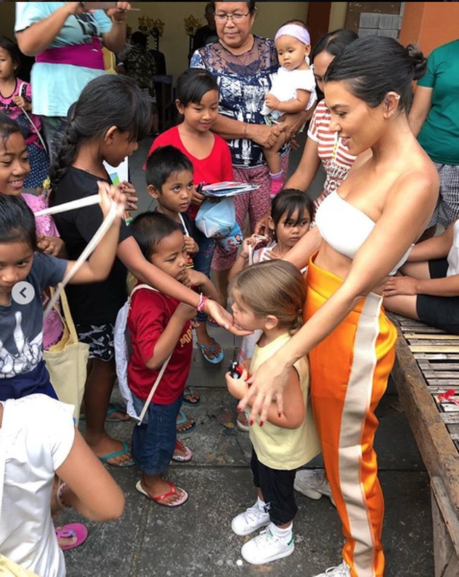 Gaya seksi Kourtney dengan kemben putih dan celana bergaya sporty saat dirinya bermain dengan anak-anak warga lokal. (Foto: Dok. Instagram/kourtneykardashian)