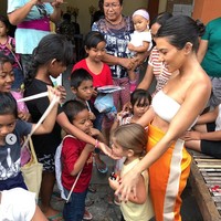 Gaya seksi Kourtney dengan kemben putih dan celana bergaya sporty saat dirinya bermain dengan anak-anak warga lokal. (Foto: Dok. Instagram/kourtneykardashian)