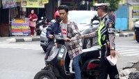 Polisi menilang pengendara motor yang tak memiliki plat kendaraan.