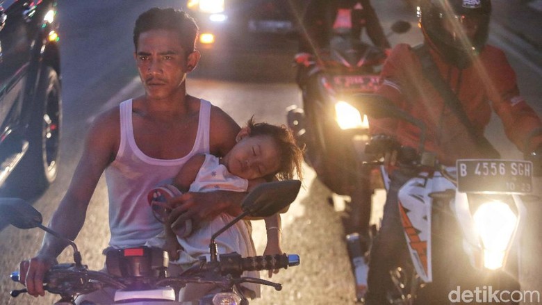 Seorang bapak memegang anaknya yang tertidur saat naik motor Foto: Pradita Utama Seorang bapak memegang anaknya yang tertidur saat naik motor Foto: Pradita Utama