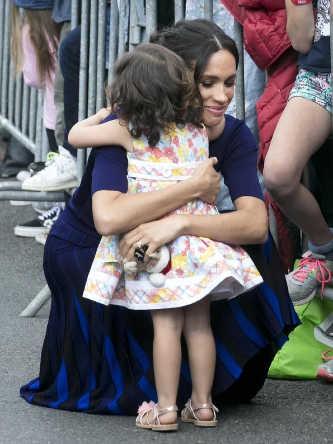 Meghan memeluk gadis kecil saat menyapa warga lokal. Antusias, warga berbondong-bondong datang untuk melihat Meghan dan Pangeran Harry secara langsung. (Foto: Dominic Lipinski-Pool/Getty Images)