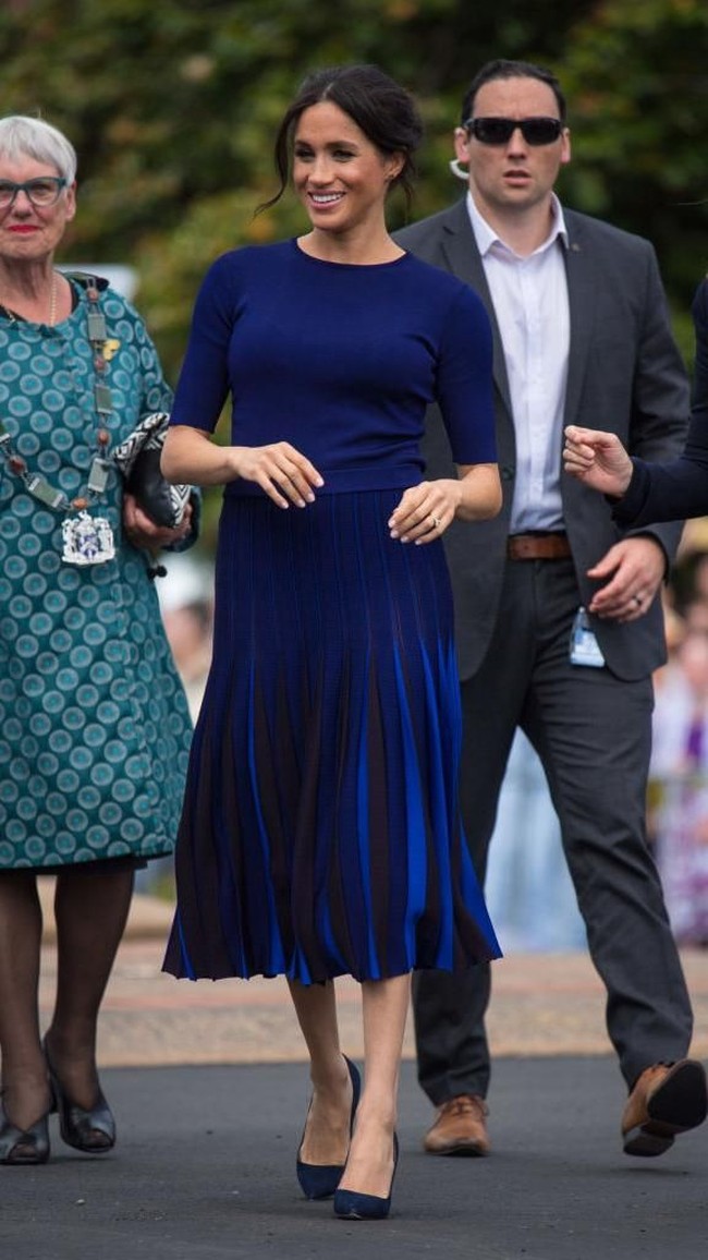 Meghan menyempurnakan gayanya dengan sepasang suede heels berwarna navy favoritnya dari label Manolo Blahnik. (Foto: Dominic Lipinski-Pool/Getty Images)