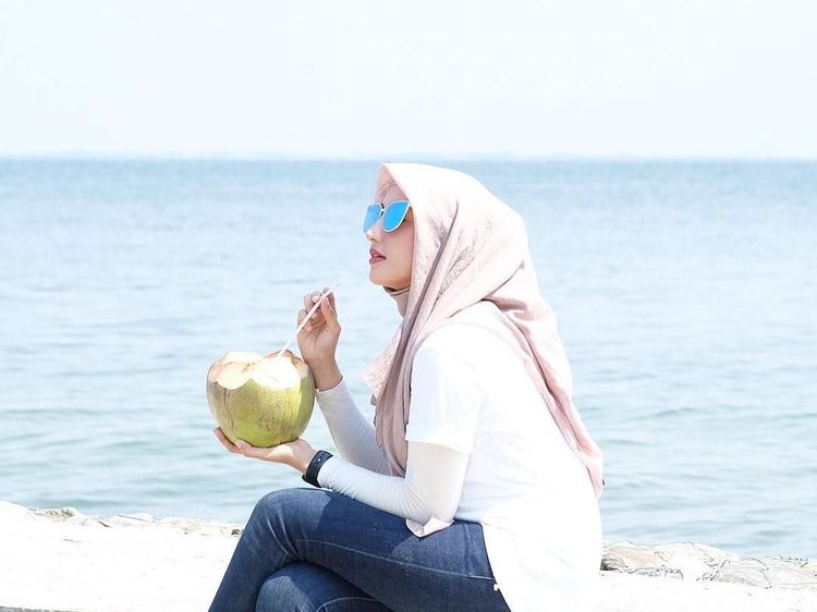 Cantiknya Dokter Nadia Alaydrus Saat Minum Es Kelapa di Pinggir Pantai